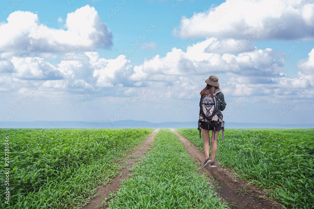 Alone young girl walking on the dirt road.