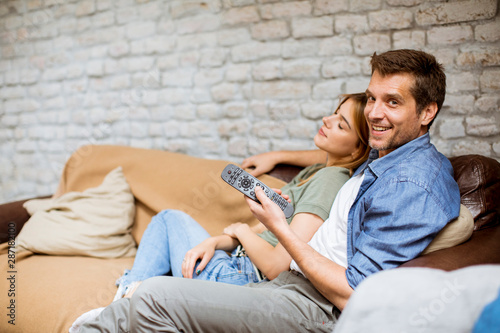 Smiling young couple relaxing and watching TV at home