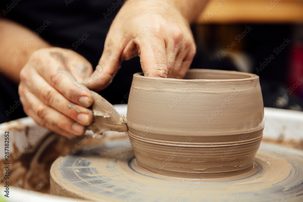 Close up detail view at an artist makes clay pottery on a spin wheel