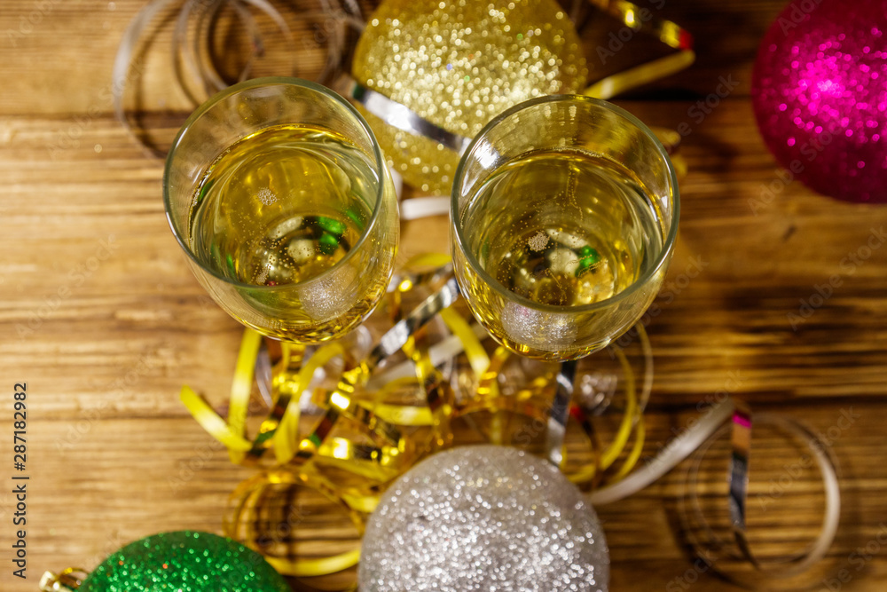 Two glasses of champagne and festive Christmas decorations on wooden table. Top view. Christmas and New Year celebration