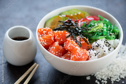 Closeup of poke with salmon fillet in a white bowl, selective focus, studio shot