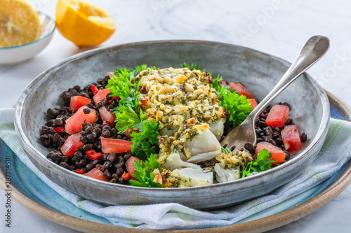 Pesto-crusted cod with Puy lentils and tomatoes in a bowl © beataaldridge