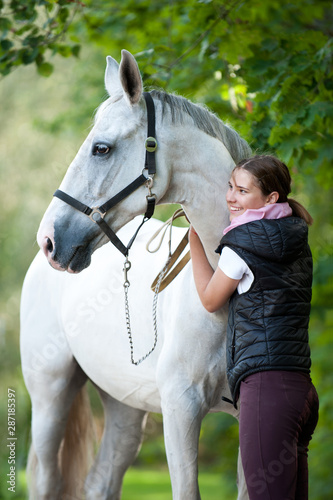 Young cheerful lady coach with her favorite white horse