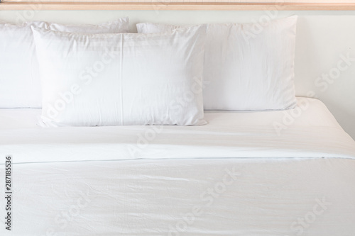 Three white pillows neatly arranged on the white bed. Hotel service.