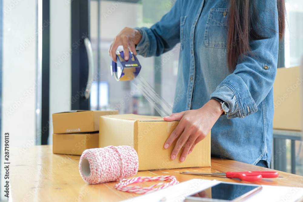 Teenage girls are packing products in boxes and using clear adhesive tape to deliver to customers.