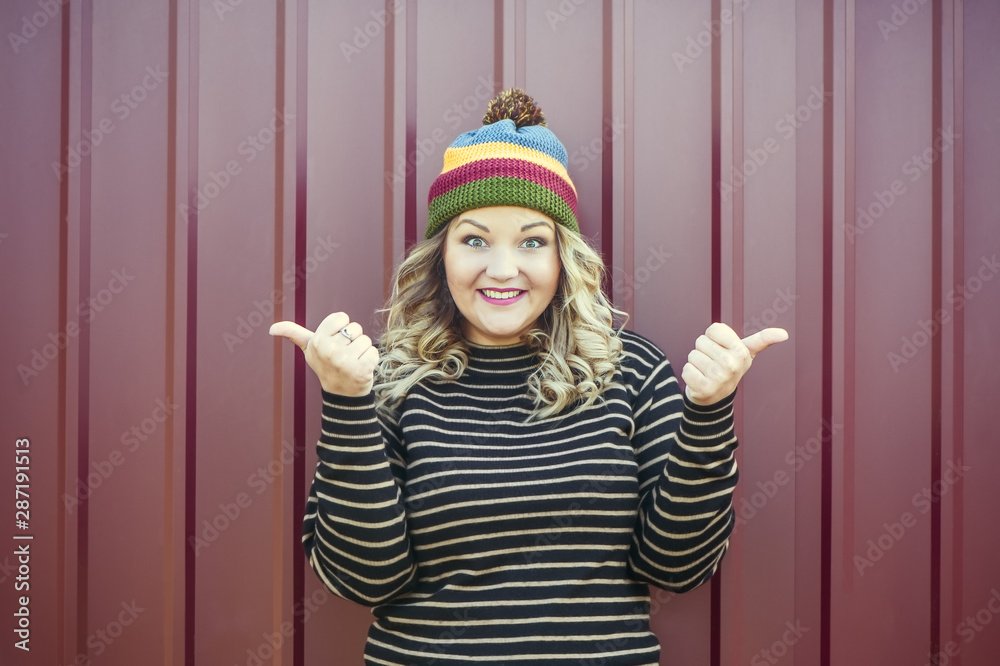 Satisfied and happy girl with a smile holds thumbs up, concept of good luck and joy. A dream come true!.Bright photo of a beautiful girl in an autumn hat and a sweater on a stylish background Satisfied and happy girl with a smile holds thumbs up, concept of good luck and joy. A dream come true!.Bright photo of a beautiful girl in an autumn hat and a sweater on a stylish background