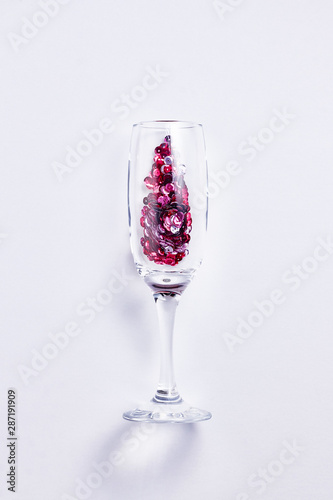 Christmas and New Year or holiday festive card. Champagne glass with pink sparkles over white background