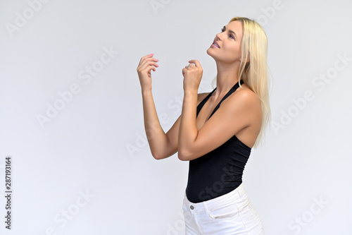 Portrait of a cute girl, a young blonde woman with beautiful curly hair in a black T-shirt and white shorts on a white background. Beauty, brightness, smile, emotions.
