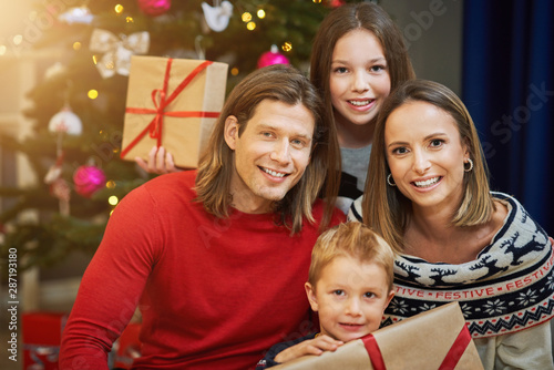 Beautiful family with presents over Christmas tree