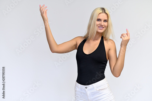 Portrait of a cute girl, a young blonde woman with beautiful curly hair in a black T-shirt and white shorts on a white background. Beauty, brightness, smile, emotions. © Вячеслав Чичаев