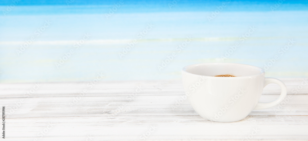 Coffee cup on white wood table with bright blue sea background