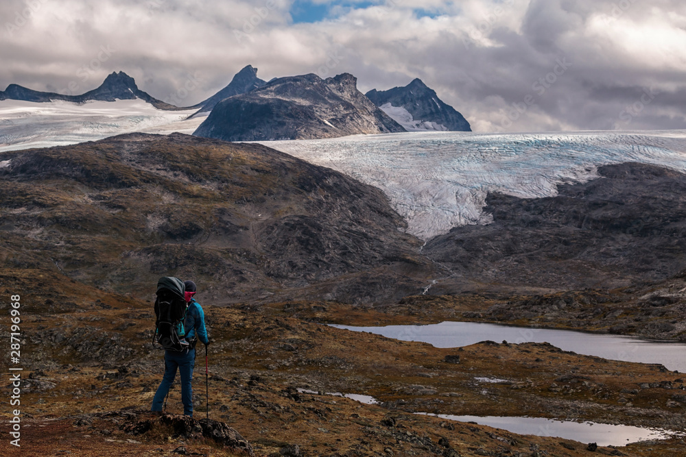 Hiker with kid in backback looking at smorstabbreen glacier in Jotunheimen NP in Norway