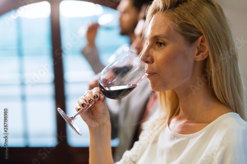Beautiful blonde woman drinking glass of red wine