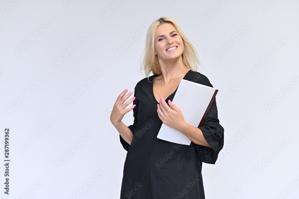 Portrait of a cute girl, a young blonde woman with beautiful curly hair in a black dress on a white background with a folder in her hands. Beauty, brightness, smile, emotions.