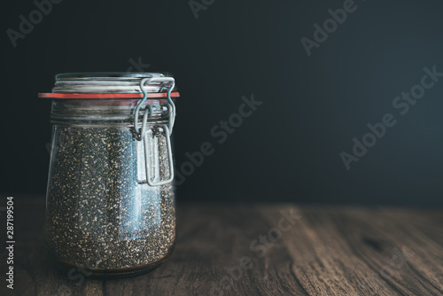 close-up shot of chia seeds in glass weck jar on wooden table against dark background photo