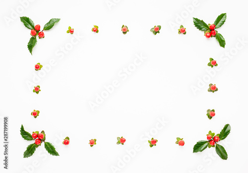 Christmas composition with branches of spruce and holly with red berries on white background. Merry christmas greeting card with empty space for holiday text.