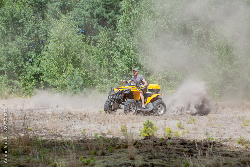 Man riding a yellow quad ATV all terrain vehicle on a sandy forest. Extreme sport motion, adventure, tourist attraction. Man riding a yellow quad ATV all terrain vehicle on a sandy forest. Extreme sport motion, adventure, tourist attraction.