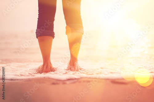 Splash of wave hit to woman legs at sunset beach abstract background.