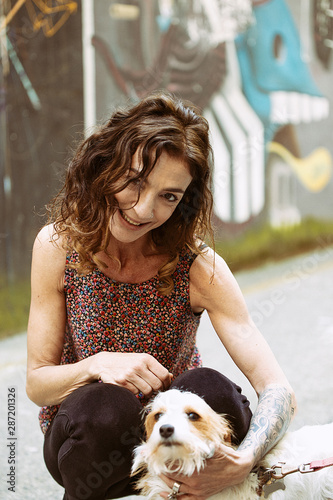 Happy woman strocking her dog in alley, San Sebastian photo