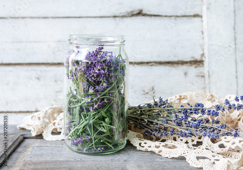A glass jar full of freshly harvested lavender blossoms in vintage traditional environment