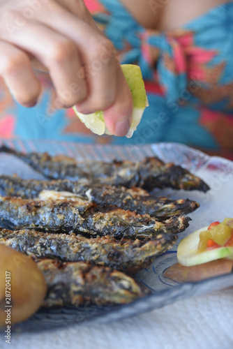 Lison, Portugal: A diner squeezes lemon juice onto freshly grilled Sardines photo