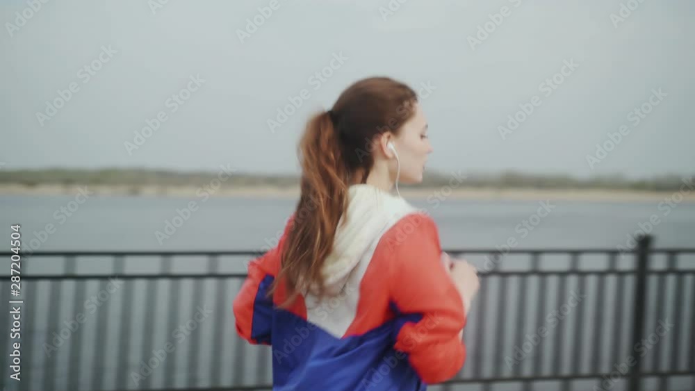 Sporty woman running along the embankment. Girl sport fitness model in sporty running clothes with headphones Sporty woman running along the embankment. Girl sport fitness model in sporty running clothes with headphones