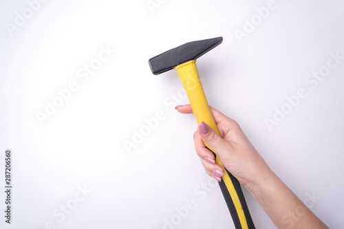 Fashion woman's hand with a gentle manicure holds a tool. Safe work, place for an inscription. View from above. White background, contrasting shadow.