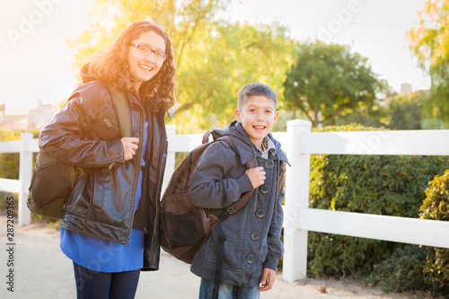 Hispanic Brother and Sister Wearing Backpacks Walking © Andy Dean