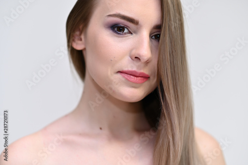 A close-up portrait of a cute girl, a young woman with beautiful curly hair on a white background with excellent face skin and outstanding fashionable make-up. Beauty, brightness.