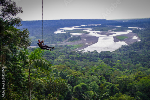 Tourist having fun in the air held by a rope. Fabulous Amazonian landscape where you can appreciate the immensity of the jungle and a huge river. photo