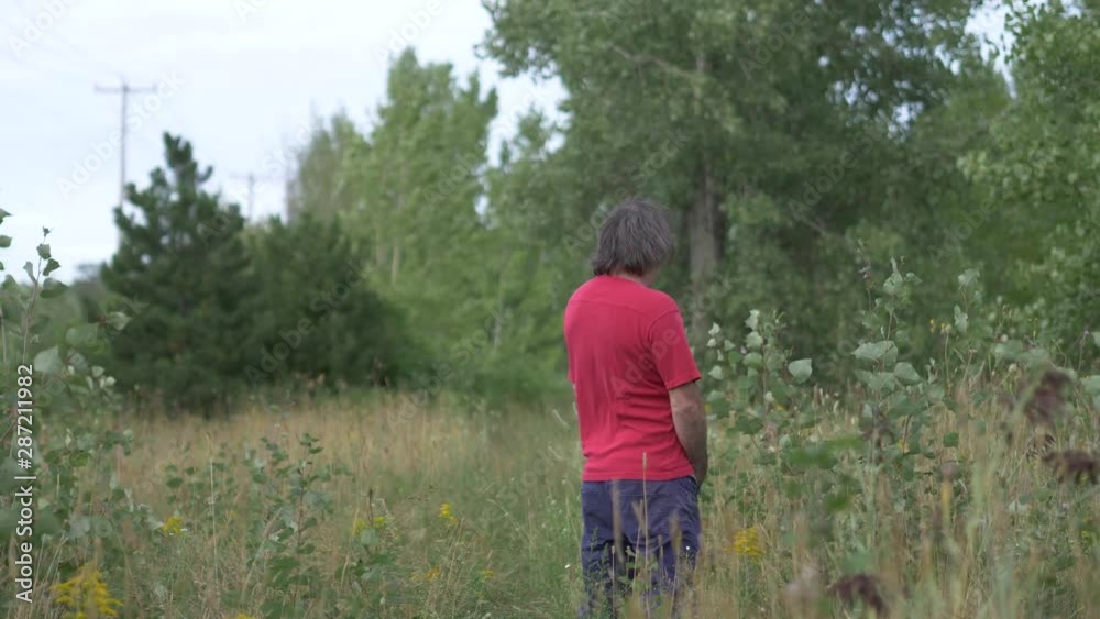 Man urinating in nature in a field during summer. Man urinating in nature in a field during summer.