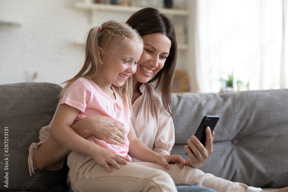 Obraz premium Mother and daughter using smartphone having fun online