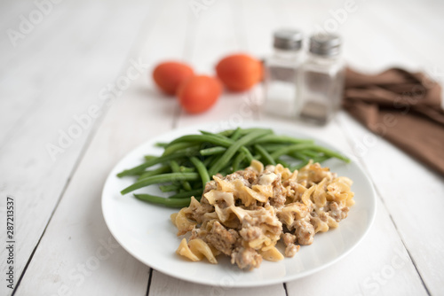 Turkey Stroganoff on white wood table with green beans and seasonings