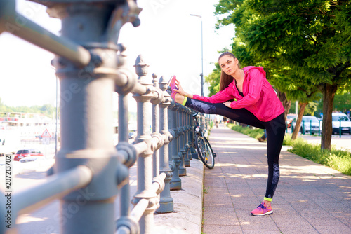 Shot of young woman stretching after running in the street