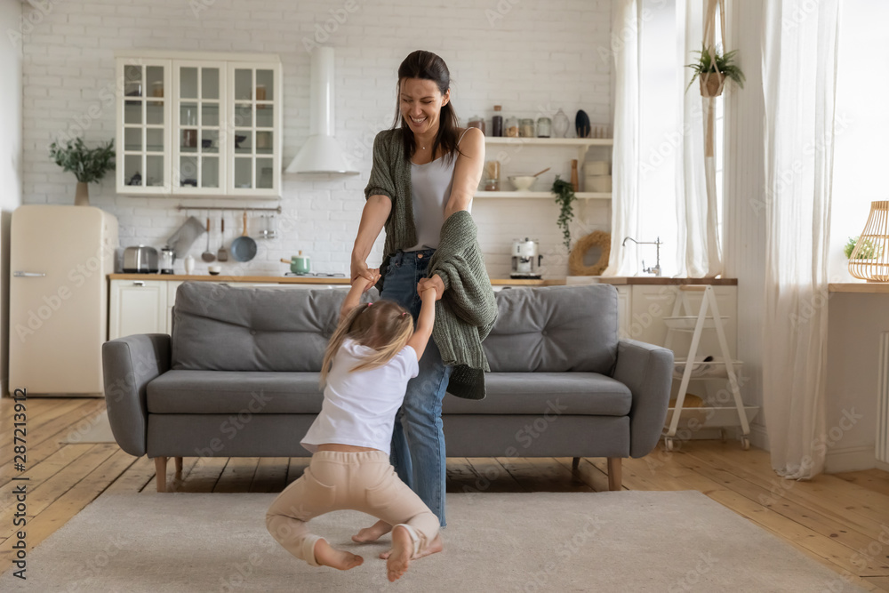 Beautiful woman spinning in circle little daughter in living room Beautiful woman spinning in circle little daughter in living room
