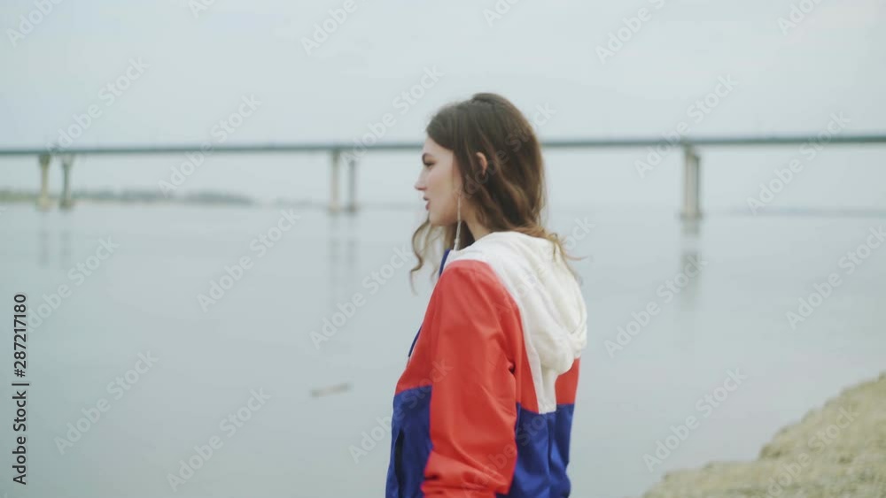 Beautiful young woman walking near the river. Young woman walking along the water Beautiful young woman walking near the river. Young woman walking along the water