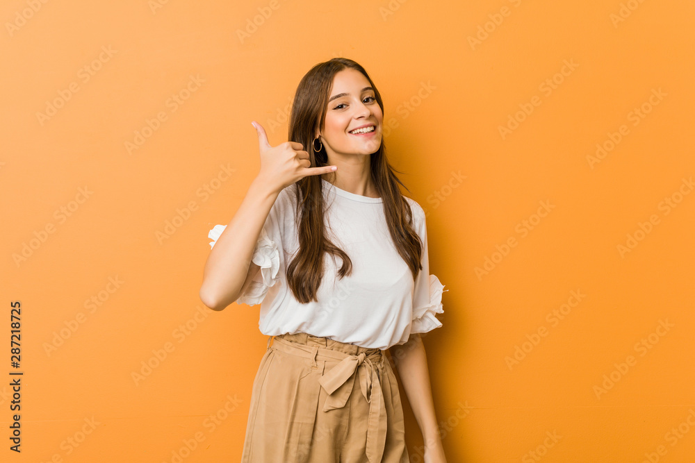 Young caucasian woman showing a mobile phone call gesture with fingers. Young caucasian woman showing a mobile phone call gesture with fingers.