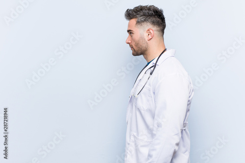 Young handsome doctor man gazing left, sideways pose.