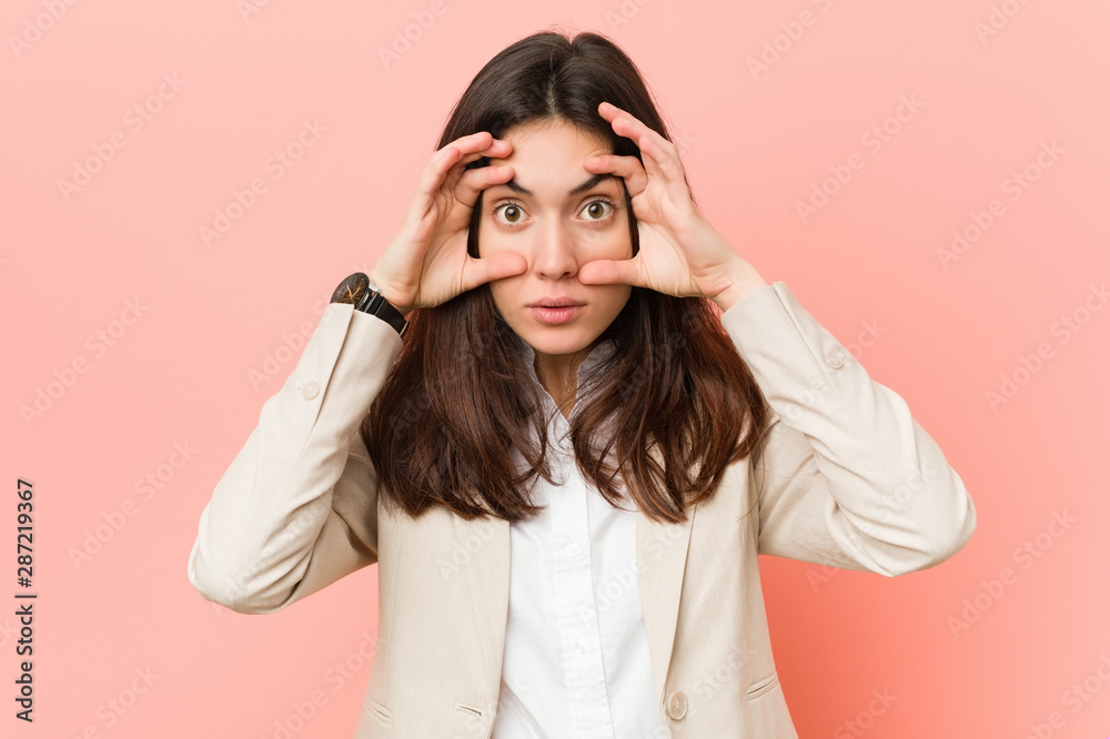Young brunette business woman against a pink background keeping eyes opened to find a success opportunity. Young brunette business woman against a pink background keeping eyes opened to find a success opportunity.