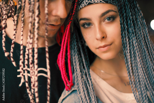 Unconventional young couple portrait at the night city with african colorful pigtails, trendy hairstyle
