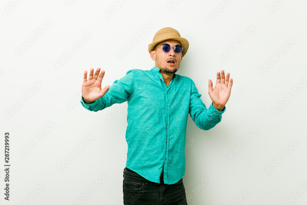 Young hispanic man wearing a summer clothes being shocked due to an imminent danger