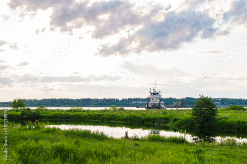 landscape of a river delta with a tugboat and a dredger in the background © Evgeny
