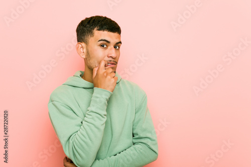 Young hispanic sport man relaxed thinking about something looking at a copy space.