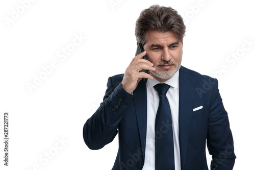 Thoughtful businessman walking on his phone and looking down