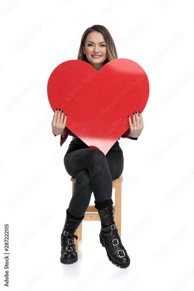 casual woman sitting with a big heart on hands casual woman sitting with a big heart on hands