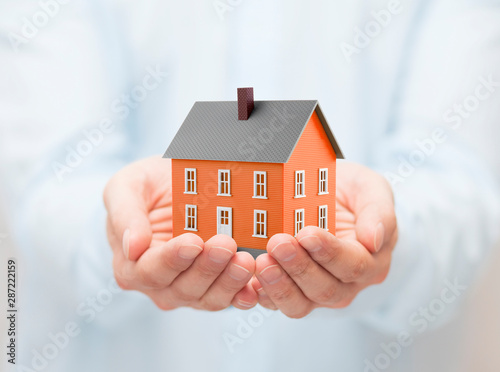 Small orange toy house in hands 