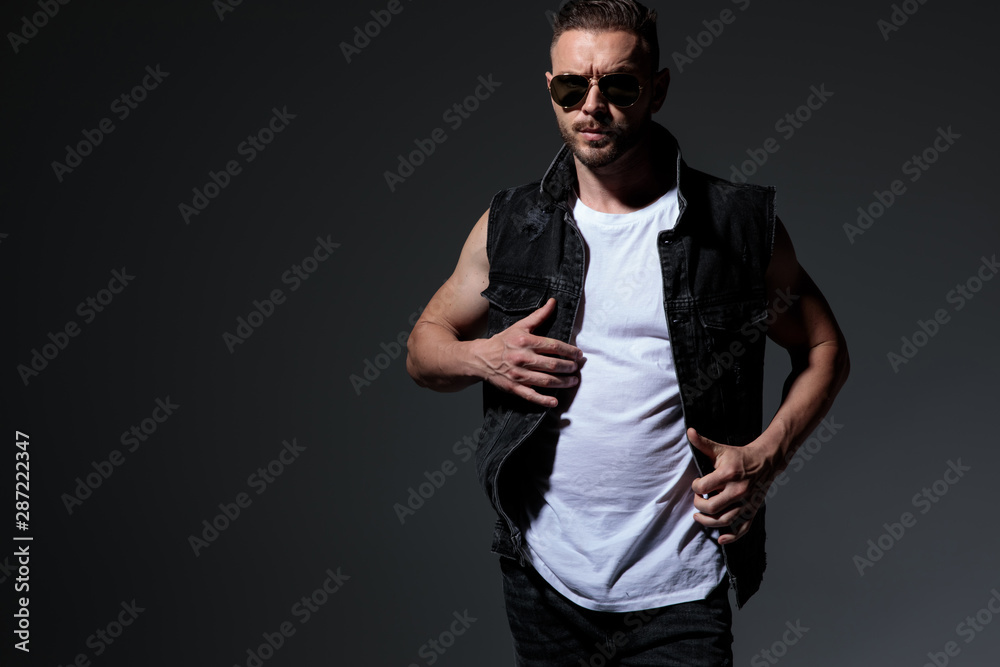 Obraz premium cool dramatic young strong man fixing his jeans jacket collar