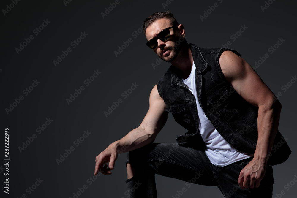cool young man in jeans clothes resting elbow on knee cool young man in jeans clothes resting elbow on knee