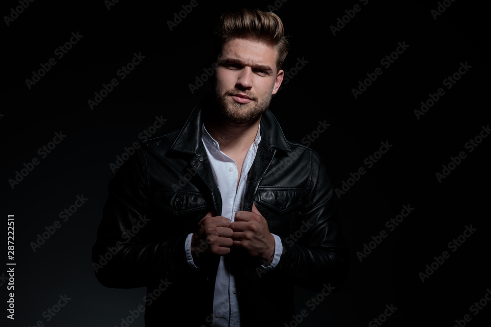 unhappy of angry young man holding his leather jacket's collar