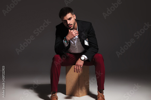 pensive young attractive man sitting on wood box